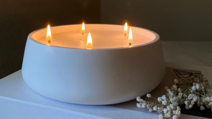White ceramic bowl with four lit candles on a dark background